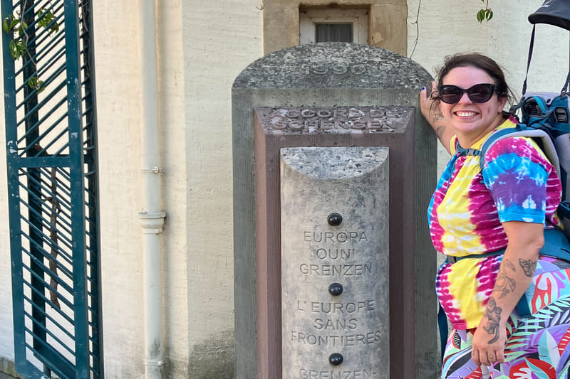 Roberta Schmoi apoiada no marco do tratado de Schengen onde a trilha do Schengen dream loop começa